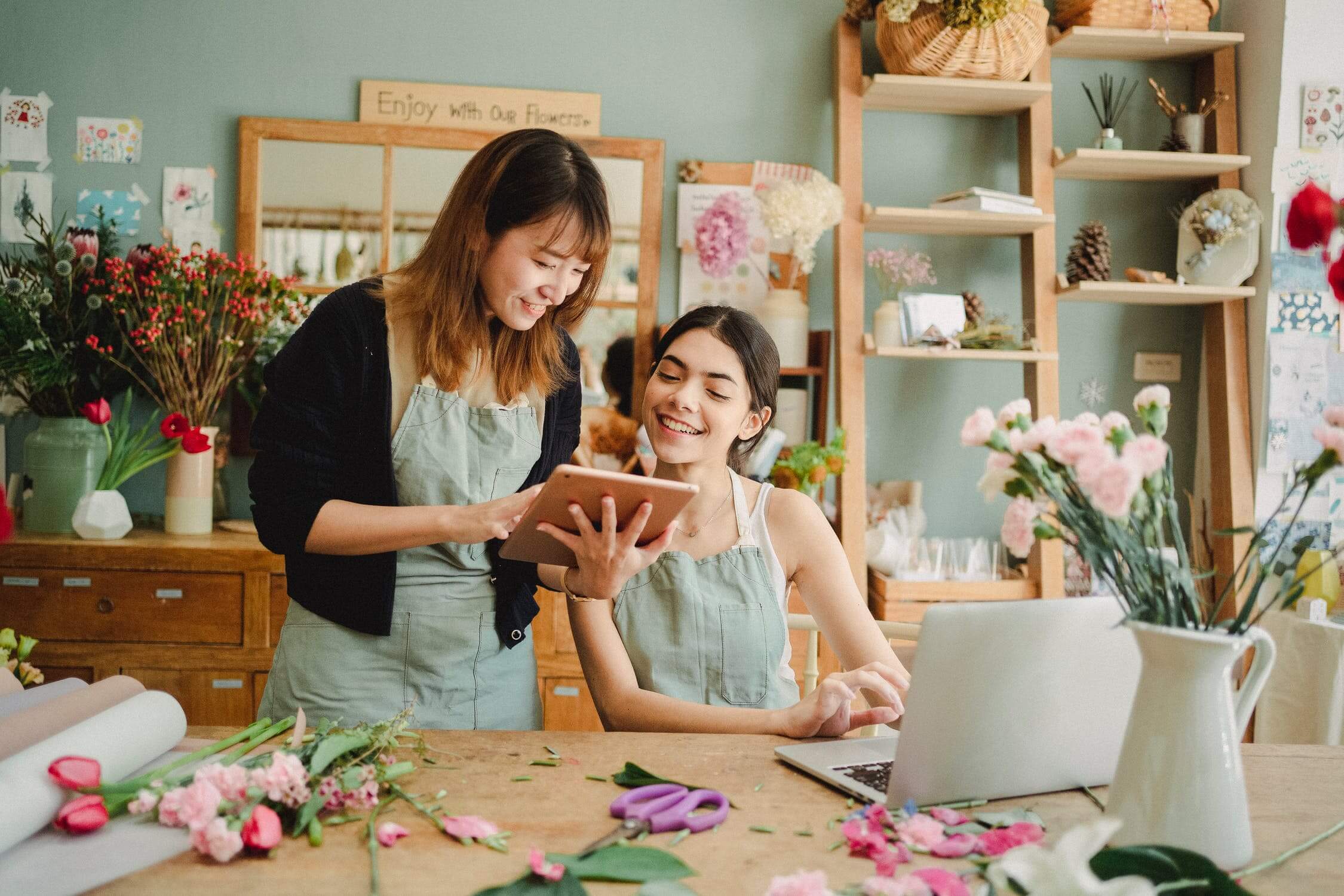 a woman and a girl standing next to a table with a laptop