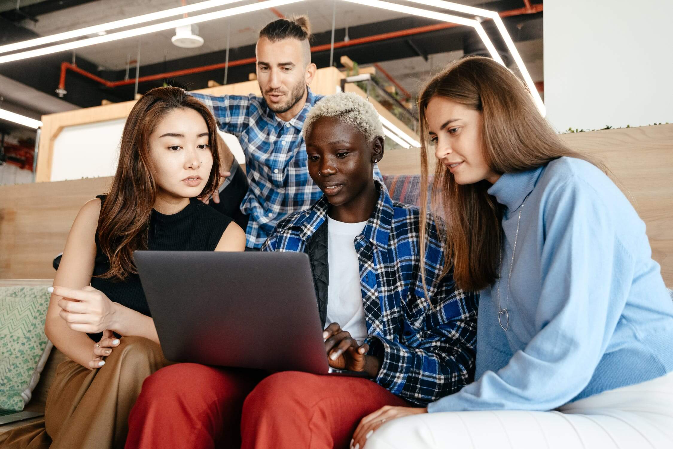 a group of people sitting on a couch looking at a laptop